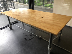 Work desk, 4 seats, steel frame, wood top, maple color, with wheels.