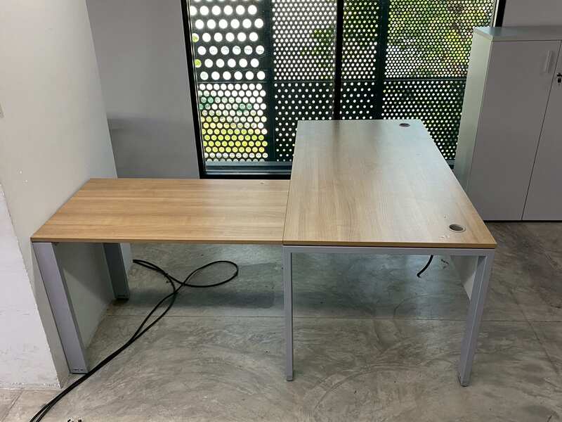L-shaped corner desk with steel legs and light brown wood top, includes power strip. PROFLEX brand.