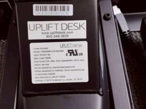 Uplift Desk, adjustable standing desk, L-shaped, black steel legs, with power strip, 150 cm wide.