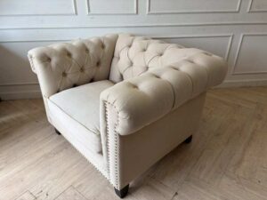 Chesterfield style armchair with cream-colored fabric and button tufting. (1)