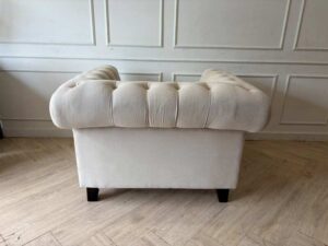 Chesterfield style armchair with cream-colored fabric and button tufting. (1)