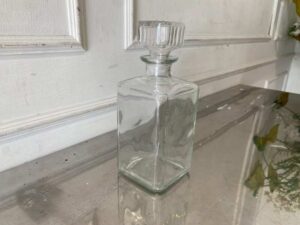 Square glass beverage bottle with a classic design.