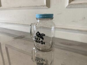 Clear glass mason jar with handle and lid.