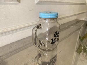 Clear glass mason jar with handle and lid.