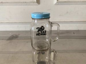 Clear glass mason jar with handle and lid.