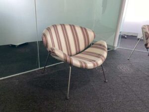 Guest chair with metal legs and cream fabric seat.