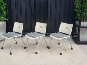 Chair with steel legs, casters, and a gray fabric cushion.