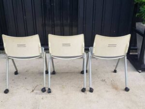 Chair with steel legs, casters, and a gray fabric cushion.