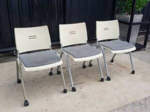 Chair with steel legs, casters, and a gray fabric cushion.