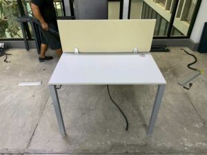 Two-seater group workstation with grey steel legs, cream-colored partition, and power strip.