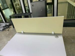 Two-seater group workstation with grey steel legs, cream-colored partition, and power strip.