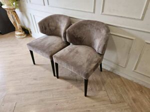 Dining chair with gray velvet upholstery and wooden legs.