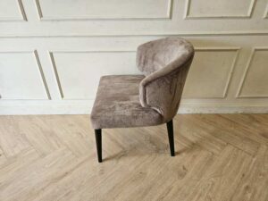 Dining chair with gray velvet upholstery and wooden legs.