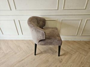 Dining chair with gray velvet upholstery and wooden legs.
