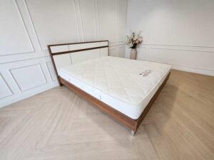 6-foot wooden bed frame with polished iron legs in a brown wood grain pattern, and a 6-foot white pocket spring mattress, Synda brand.