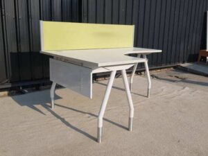 L-shaped corner desk with white steel legs and light yellow partition. 160 cm wide.