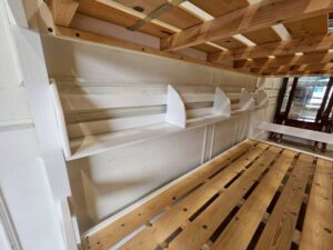 White and blue wooden bunk bed for children with shelves.
