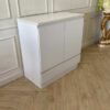 White wooden shoe cabinet with two doors and two drawers.