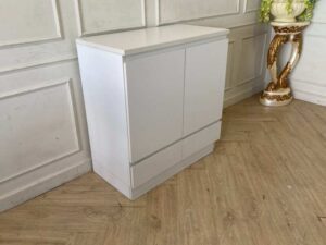 White wooden shoe cabinet with two doors and two drawers.