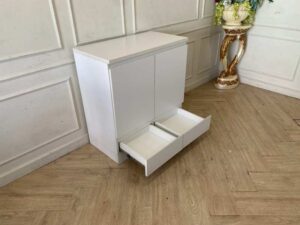 White wooden shoe cabinet with two doors and two drawers.