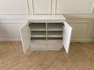 White wooden shoe cabinet with two doors and two drawers.