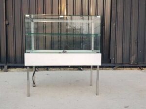 White glass display case with two doors and steel legs.