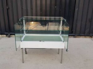 White glass display case with two doors and steel legs.