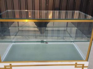 White glass display case with two doors and steel legs.