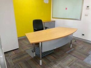 Curved-top office desk with light brown wood top and steel legs, MOFLEX brand.