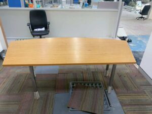 Curved-top office desk with light brown wood top and steel legs, MOFLEX brand.