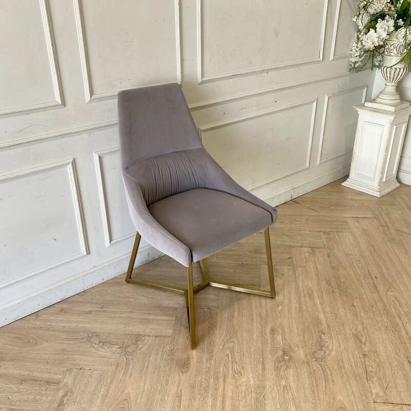 Chair with gold-colored metal legs and grey velvet seat.