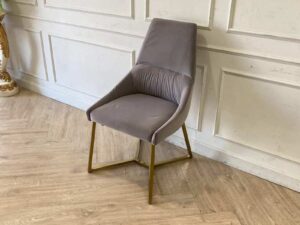 Chair with gold-colored metal legs and grey velvet seat.