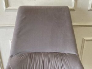 Chair with gold-colored metal legs and grey velvet seat.