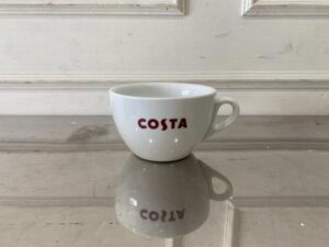 White ceramic coffee cup set with handle and saucer, Costa Coffee brand.
