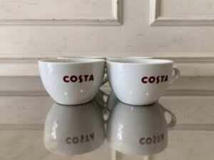 White ceramic coffee cup set with handle and saucer, Costa Coffee brand.
