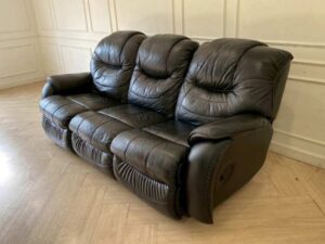 Black 3-seater leather sofa bed with a central cushion that folds down to become a cup holder._DDHQY5KRSU