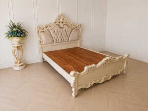 6-foot Louis XV bed with beige nude velvet headboard and carved floral frame.