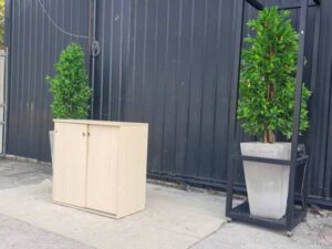 Cream-colored, wooden-framed filing cabinet with 2 sliding doors.