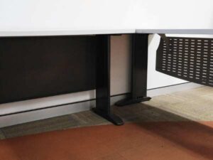 Executive desk, L-shaped corner, light gray wood top, steel legs, has a steel plate to shield the view under the desk, brand UB.