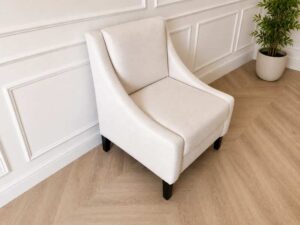 Armchair with beige fabric upholstery and dark wood legs.