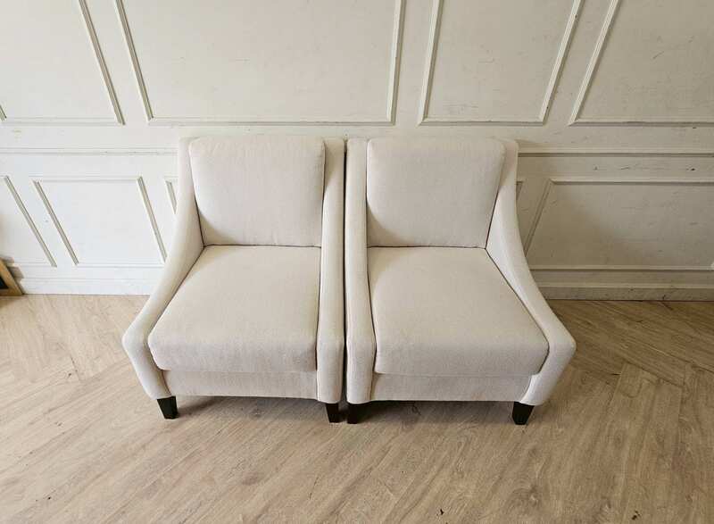 Armchair with beige fabric upholstery and dark wood legs.