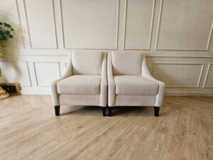 Armchair with beige fabric upholstery and dark wood legs.