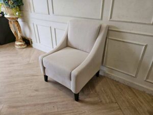 Armchair with beige fabric upholstery and dark wood legs.