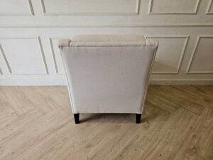 Armchair with beige fabric upholstery and dark wood legs.