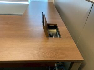 L-shaped corner desk with 3 drawers, steel legs, with rails, and power outlet.