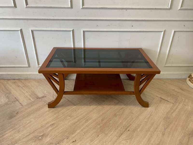 Wooden coffee table with curved legs and glass top.