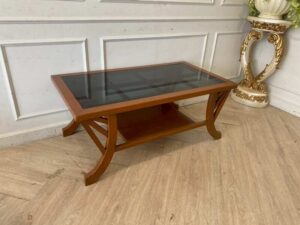 Wooden coffee table with curved legs and glass top.
