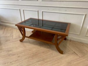 Wooden coffee table with curved legs and glass top.