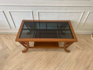 Wooden coffee table with curved legs and glass top.