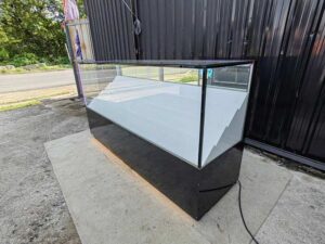 Glass Retail Display Counter with White Tiered Shelves, LED Lighting, and a Glossy Black Base